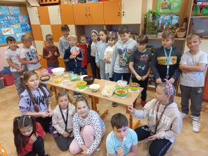 Uczniowie prezentują na wspólnym stole wykonane przez siebie sałatki warzywno - owocowe