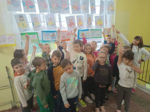 Dzieci stoją przed wystawa swoich prac na szkolnym korytarzu.