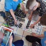 Dzieci układają z puzzli AR trasę dla ozobotów.