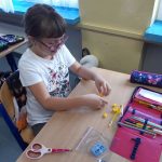 Uczennica buduje z klocków Lego kaczkę.