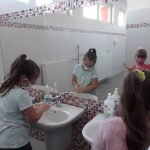 Dwie dziewczynki myją ręce w szkolnej toalecie.